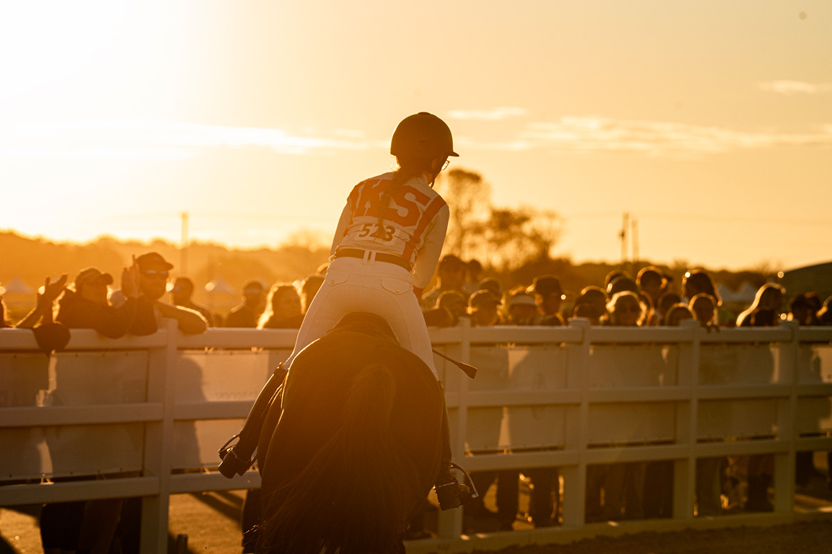 Rider at sunset, a crowd looks on and cheers