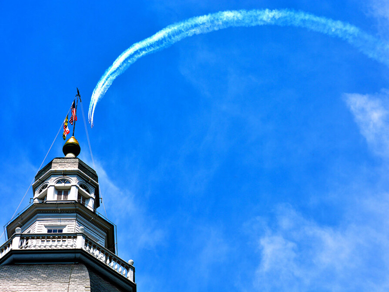 Blue Angels flying in an arch over the Maryland State House leaving a smoke trail