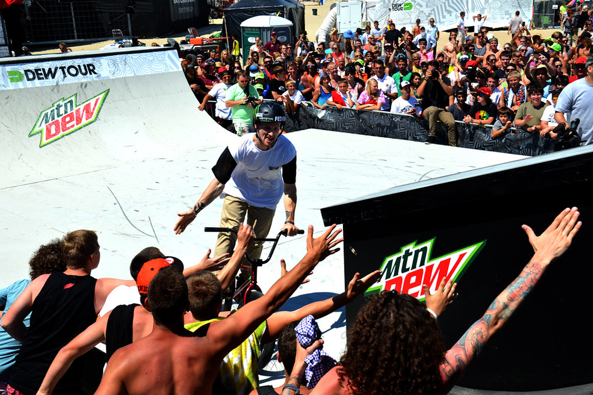 BMX rider going off the ramp hi-fiving the crowd on his way out.