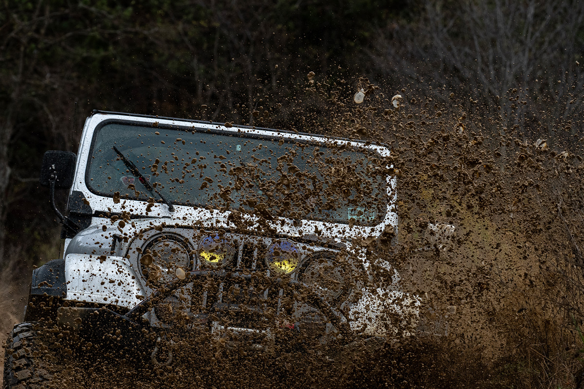 jeep plunging into a hole with mud flying off to the side