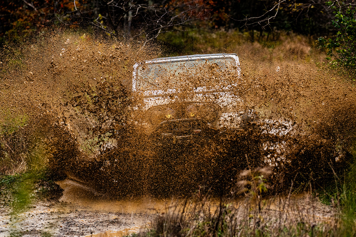 Jeep in the middle of a mud pit, you can barely see the vehicle, there is mud flying everywhere